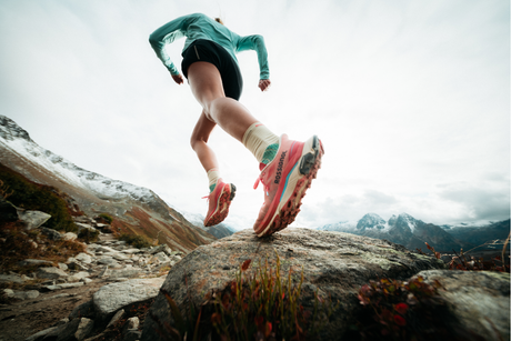 Woman wearing Rossignol Hiking Shoes running on a rocky mountain terrain on a cloudy day.